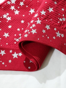 Dettaglio macro del tessuto a maglia a coste rosse con stelle argentate e trama fine