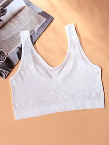 White seamless sports bra with breathable mesh texture and ribbed support on peach background