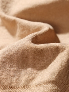 Macro texture detail of the camel knitted fabric showing seamless breathable soft material