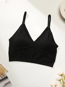 Detail of black sports bra with thin straps and V-neck on minimalist white background