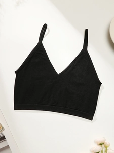 Detail of black V-neck sports bra with thin straps and wide hem on a minimalist background