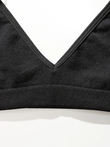 Gros plan sur l'encolure en V profond en tissu côtelé noir révélant la texture tricot