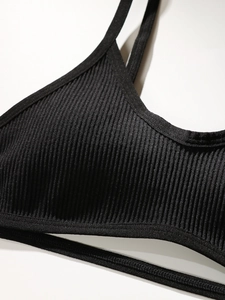 Gros plan sur la texture côtelée noire et les coutures de la brassière à fines bretelles