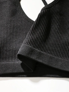 Detailed close-up of black ribbed fabric and wide elastic hem on the seamless sports bra