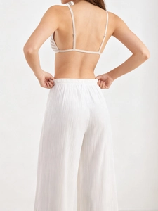 Back view of elegant white high-waist wide-leg trousers with ribbed texture and striped bra