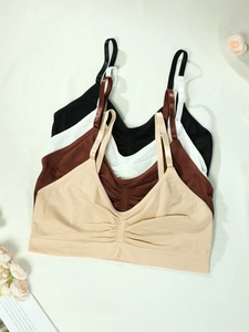 Detail of four seamless yoga bras in beige, brown, white and black colors with ruched front