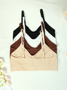 Flat lay of four seamless crop top sports bras in black, white, brown and beige colors