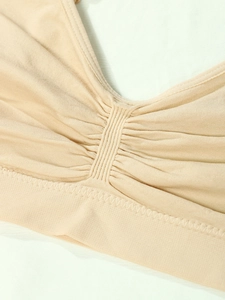 Close-up of seamless beige yoga bra featuring V-neckline and ruched center detail