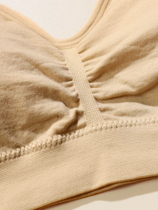 Detailed macro view of beige seamless bra fabric with pleated center and ribbed hem