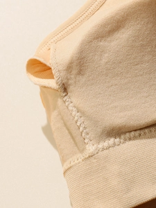 Macro view of the wavy knit edges and chest pad insertion slit on a beige sports bra