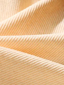 Macro shot of high-elasticity ribbed knit corduroy fabric texture in pale apricot color