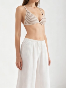 Detail of striped triangle bralette with white wide-leg trousers for a resort look