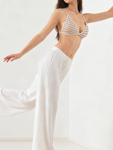 Detail of striped triangle bralette paired with white high-waist textured trousers