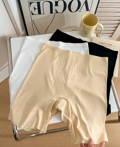 Flat lay of high-waisted seamless safety shorts in nude, white, and black on a modern chair