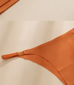 Detail shot of orange seamless panty featuring gold triple-ring metal hardware on the side