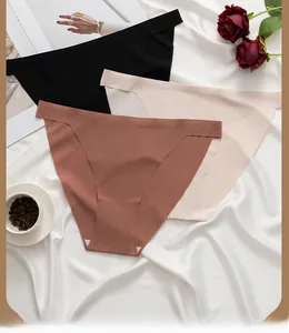 Detail view of seamless thong panties in black, beige, and brick red on silk background