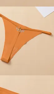 Detail of orange seamless thong with thin straps and gold metal ring decoration