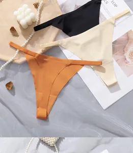 Flat lay of seamless thongs in black, beige and orange with elegant pearls and props