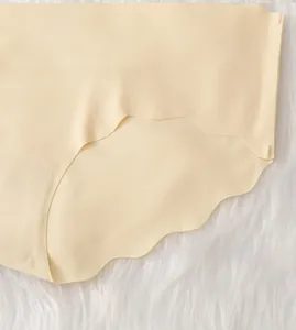 Detail of light beige ice silk panties with scalloped seamless edges on plush background
