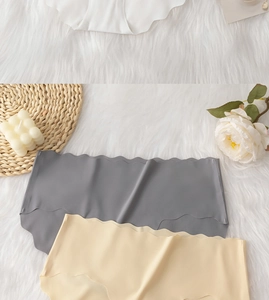 Dettaglio di mutandine senza cuciture con bordo a onda in grigio e beige su fondo di peluche