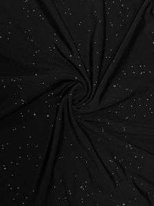 Macro shot of black ribbed knit fabric with sparkling silver sequins and spiral texture