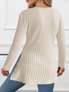 Detail of beige ribbed knit long sleeve top featuring a side slit and textured fabric