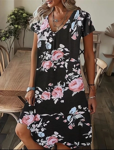 Dettaglio dell'abito estivo con scollo a V e stampa floreale di rose rosa su fondo nero