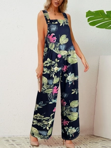 Detail of floral navy jumpsuit with tropical leaf patterns and gold strap buttons