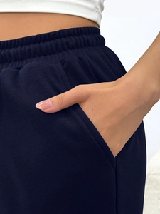 Detail view of high waist drawstring waistband and side pocket on navy joggers