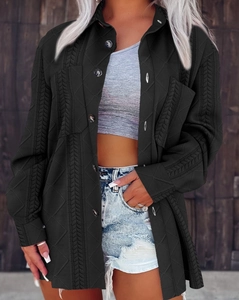 Detail of cable knit pattern and buttoned chest pockets on black knit jacket