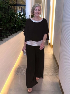 Detail of silver sequin trim on black batwing top and wide-leg trousers evening set
