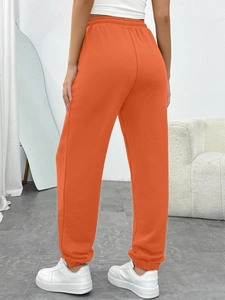 Detail view of bright orange joggers with elastic high waistband and soft cotton fabric