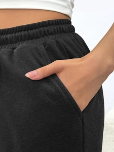 Detail of high-waist joggers showing the wide elastic waistband and side pocket texture