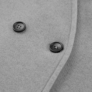 Macro view of grey wool coat featuring refined texture and black double-breasted buttons