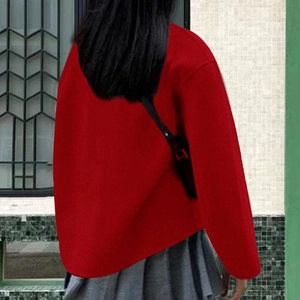 Rear view of long sleeve red coat paired with pleated skirt in a modern outdoor setting