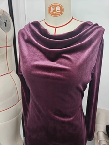 Detailed macro shot of the elegant draped neckline on the deep purple velvet dress