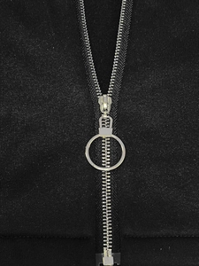 Detail of silver metal zipper with circular puller on high-quality black knit fabric