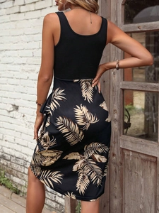 Detail view of summer dress with black sleeveless top and tropical palm leaf print skirt