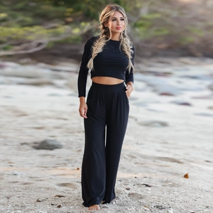 Outdoor shot of a women's black long sleeve crop top and wide leg pants set on a beach