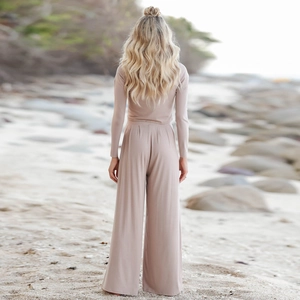 Detail of elegant two-piece long sleeve top and high-waist wide-leg trousers on beach