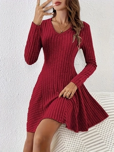 Detail of red V-neck long sleeve knit dress with ribbed texture on a white bench