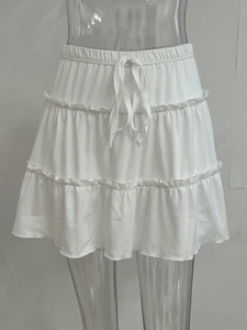Detail of white tiered mini skirt featuring elastic waist with adjustable drawstring tie
