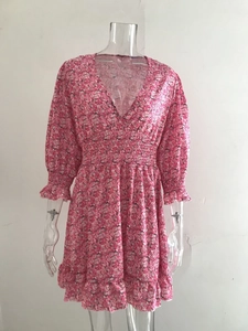 Detail of pink floral dress featuring a V-neckline and elastic ruffled waist and sleeves
