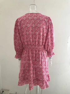 Detail view of pink floral dress featuring elastic ruffled waist and floral print texture