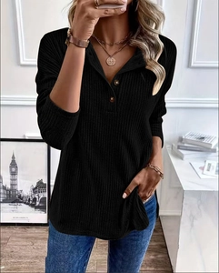 Detail of black ribbed knit long sleeve top with buttoned Henley neckline and texture