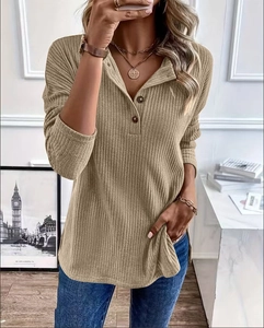 Detail of ribbed knit texture on khaki Henley sweater with wooden buttons and side slits