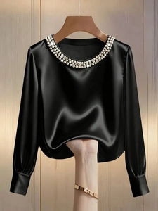 Close-up of black satin blouse featuring a luxurious pearl-decorated round neckline