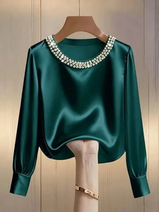 Detailed view of dark green satin shirt featuring pearl and rhinestone neckline decor