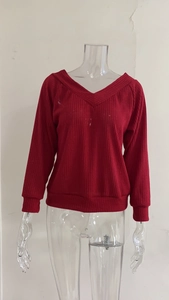 Detail of red V-neck ribbed knit sweater showing textured vertical fabric and cuffs