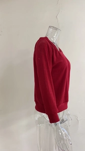 Detailed macro view of the red ribbed knit texture on long sleeve V-neck sweater fabric